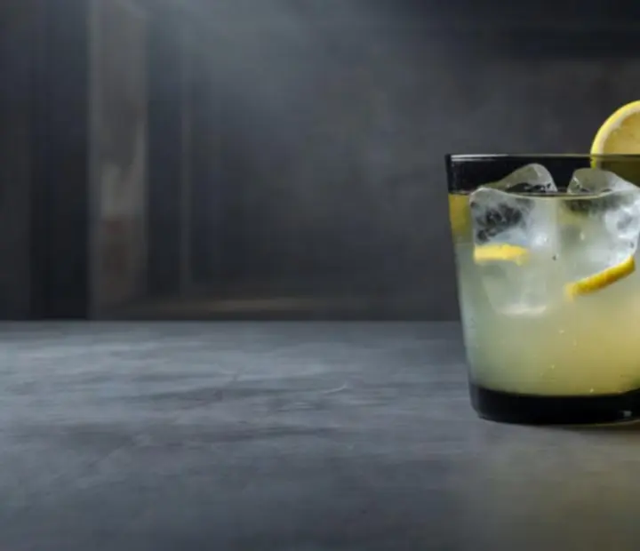 Limonade maison dans un verre sombre, éclairage chaleureux de bar